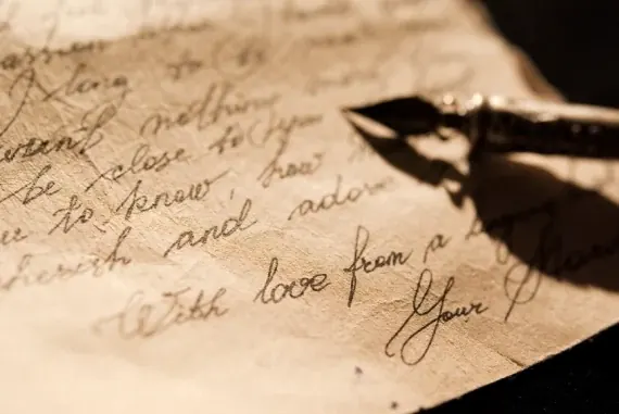 A handwritten letter in cursive on aged paper, signed “With love”, with the nib of a fountain pen resting across it